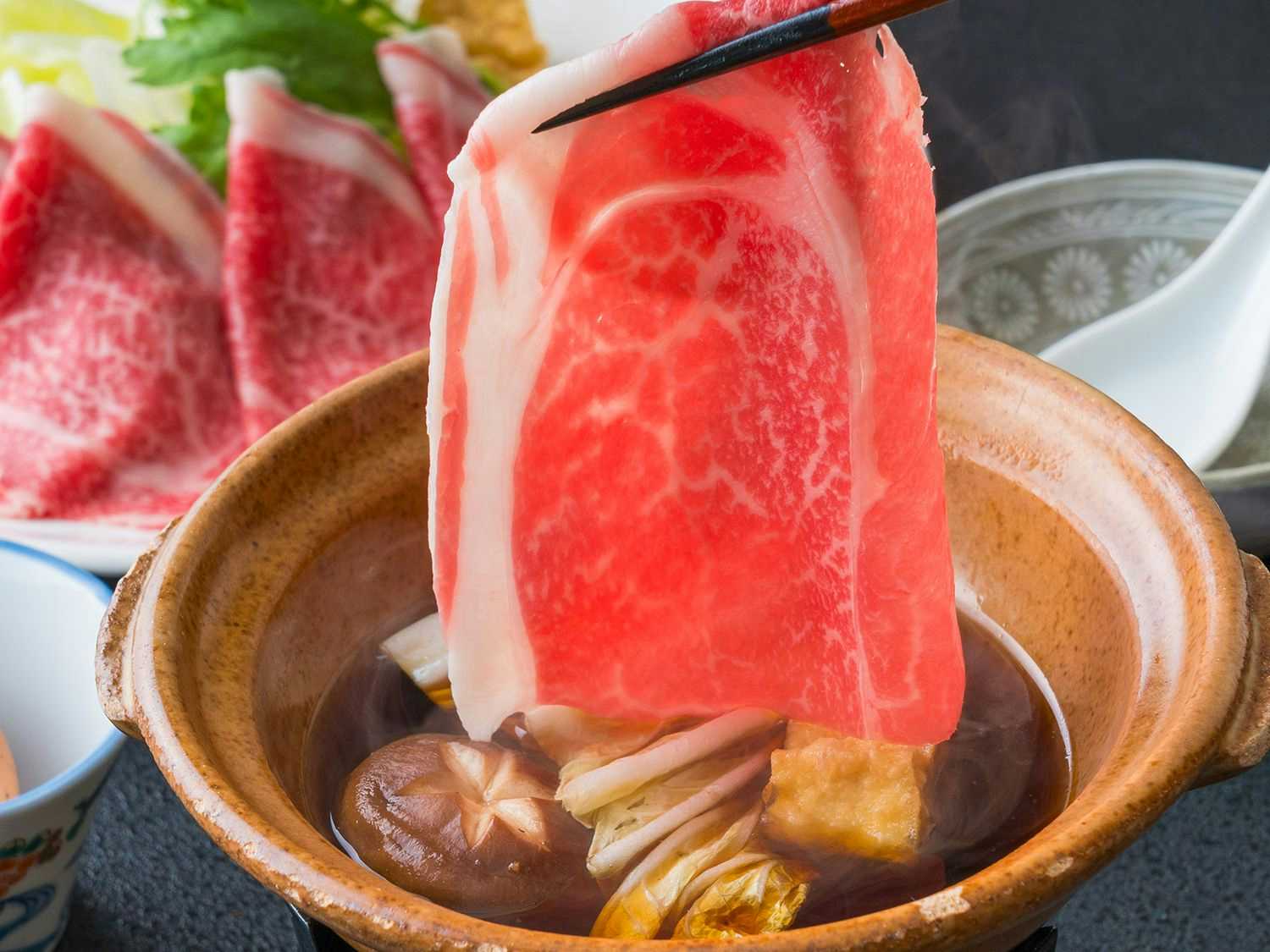 Furuyu Onsen Ougiya Ryokan with slices of marbled beef presented beside fresh vegetables.