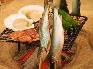 Irori no Yado Houraku with fish and vegetables grilling over an open charcoal hearth.