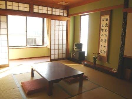 Ichirino Onsen Tsurunoya with a sunlit tatami room with low table and calligraphy scroll.