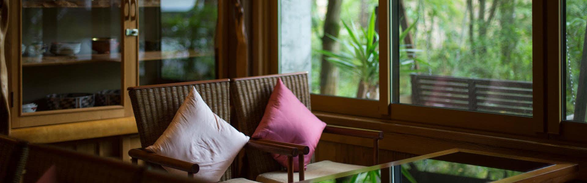 Kurokawa Onsen Ryokan Okunoyu with a quiet timber lounge overlooking dense green forest.