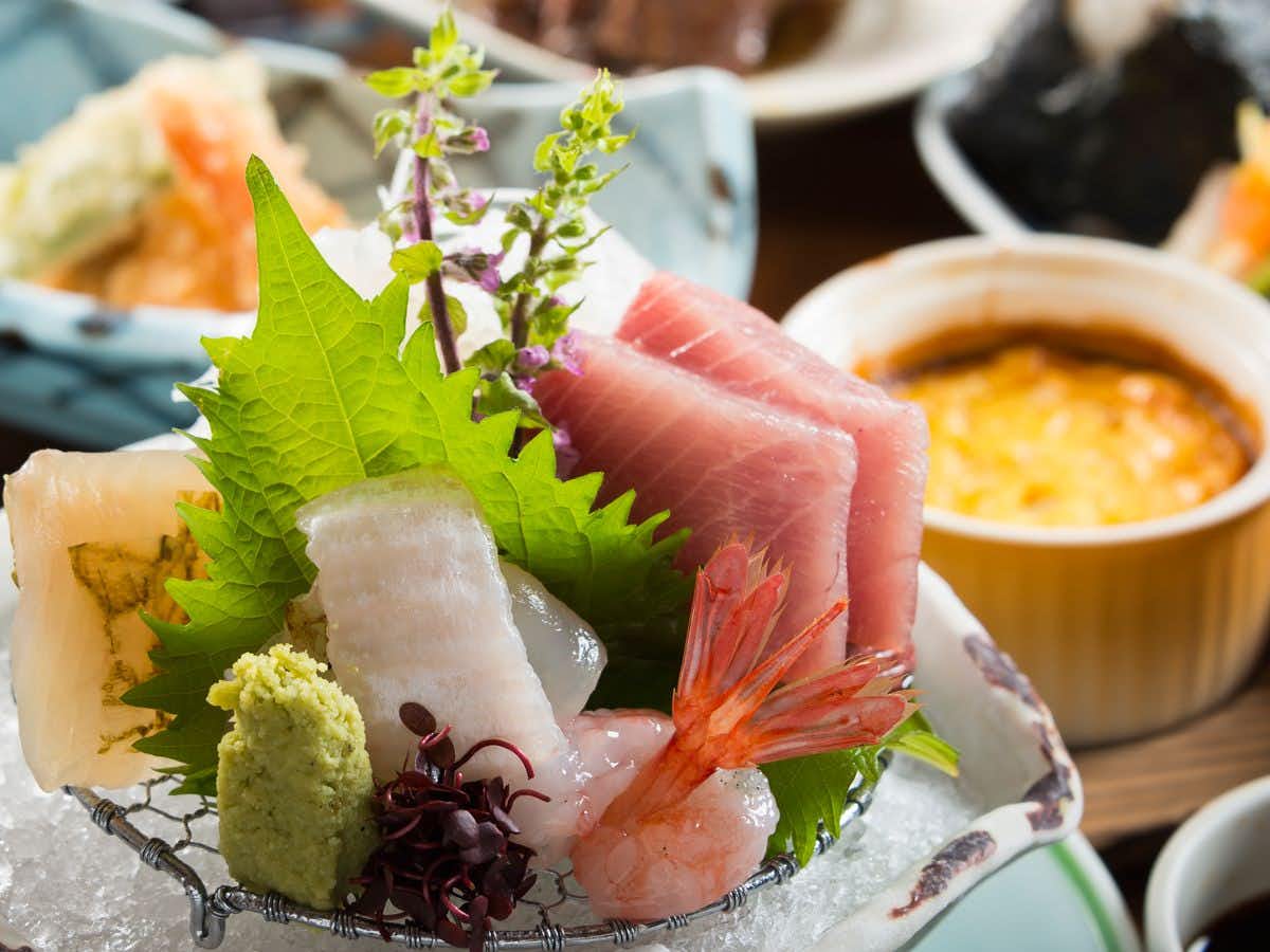 Miyajima Onsen Takinoso with this scene, where sashimi and small dishes are presented on pale ceramic plates.