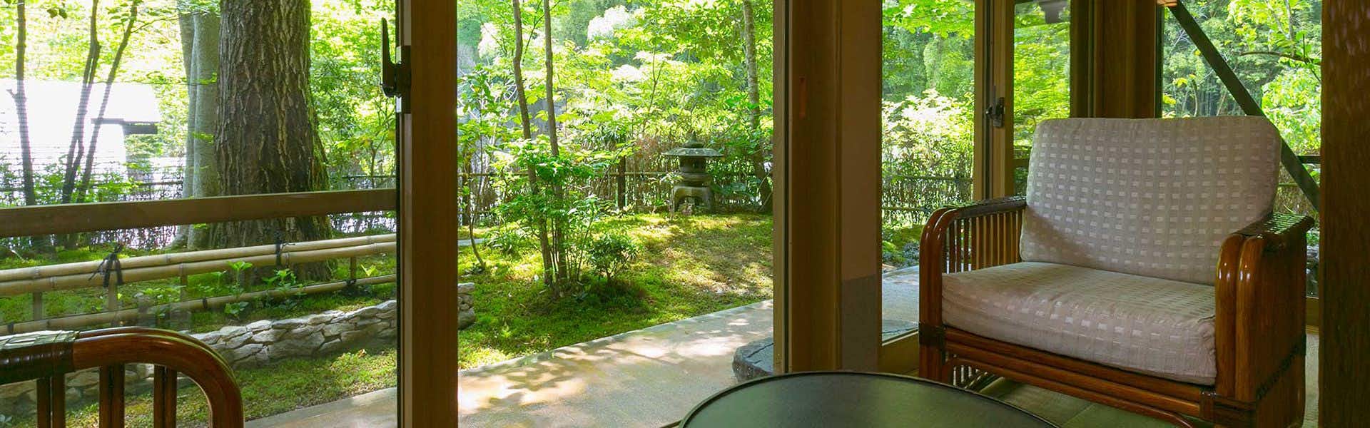 Kurokawa-so with a quiet room with armchair beside broad forest windows.