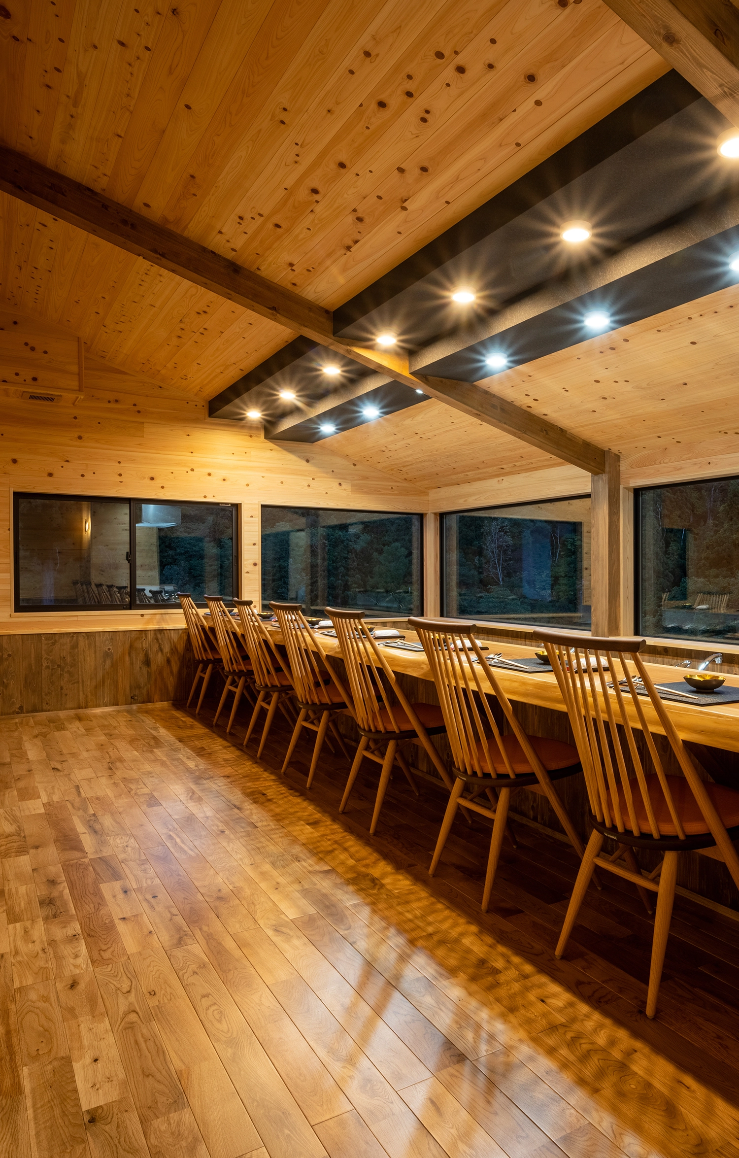Wooden dining room with a long counter and open kitchen.