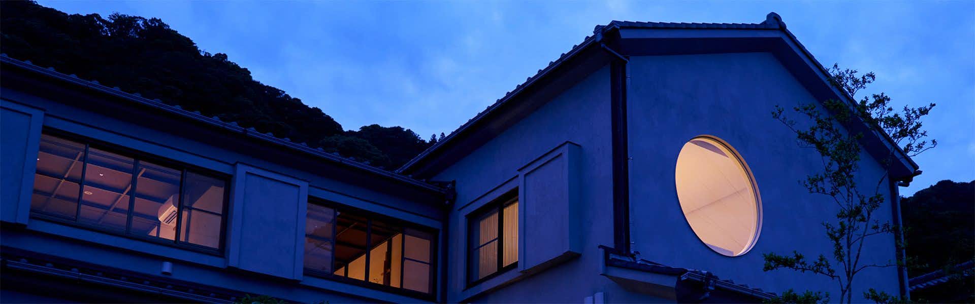 Tsuki to Maguro Ishigami a blue dusk exterior with a round illuminated window.