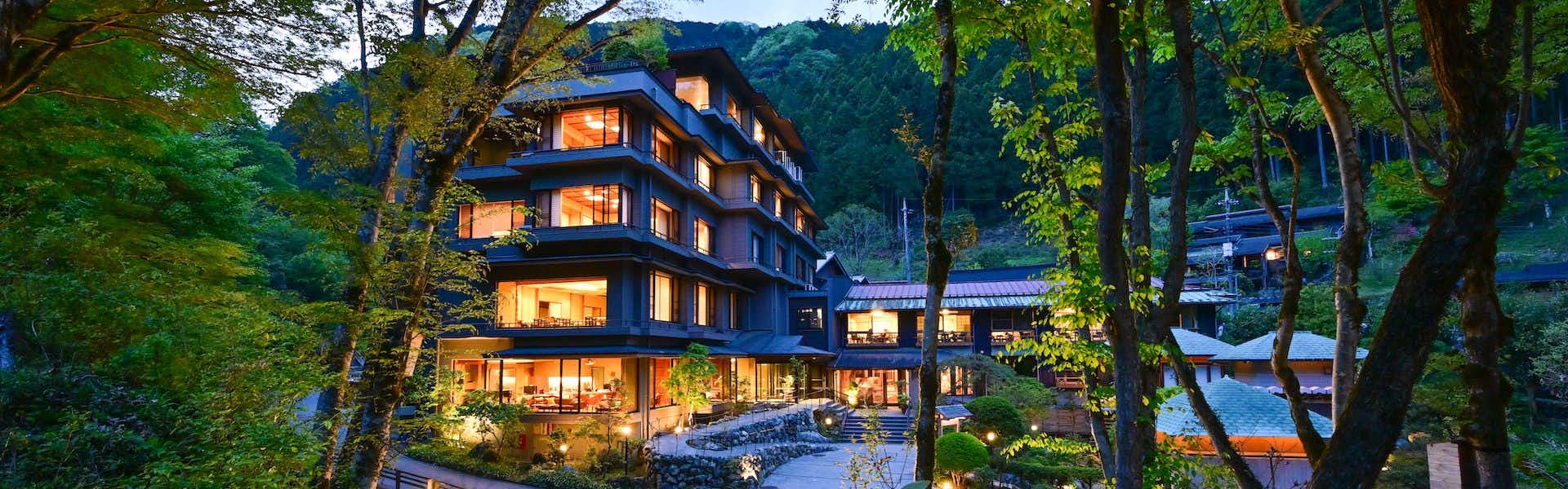 taishoukaku illuminated multi-story lodging exterior among trees at dusk