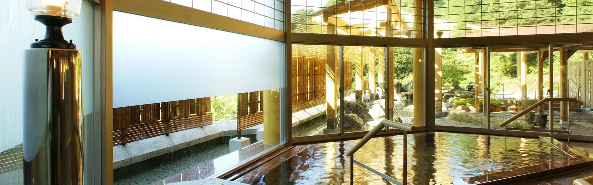 Yomogihira Onsen Izumiya indoor bath area with green water, wooden railings, and window openings