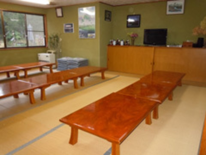 A tatami dining hall with rows of low wooden tables.
