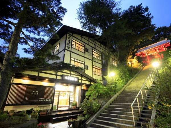 A traditional ryokan building is lit among trees at night.