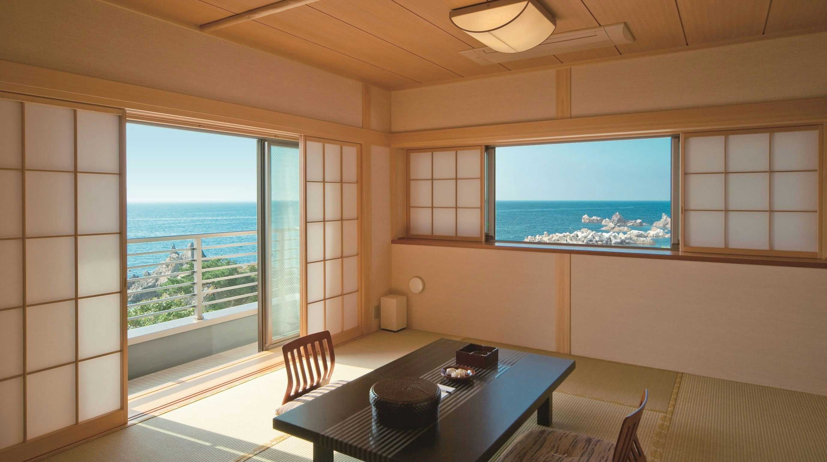 Ryokan Hamayuu Matsuiseki-an Tatami room with low black table, paper screens, corner windows, balcony, and open coastal water beyond