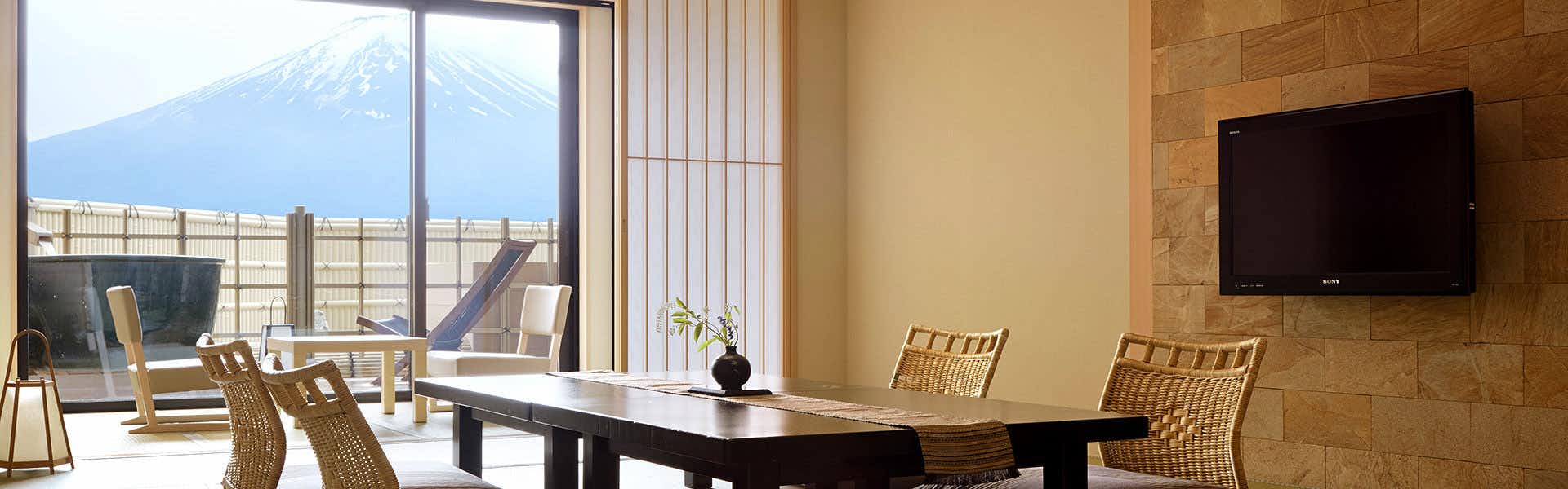 Fujikawaguchiko Onsen Konanso with a lake-view lounge with wicker chairs beside broad windows.