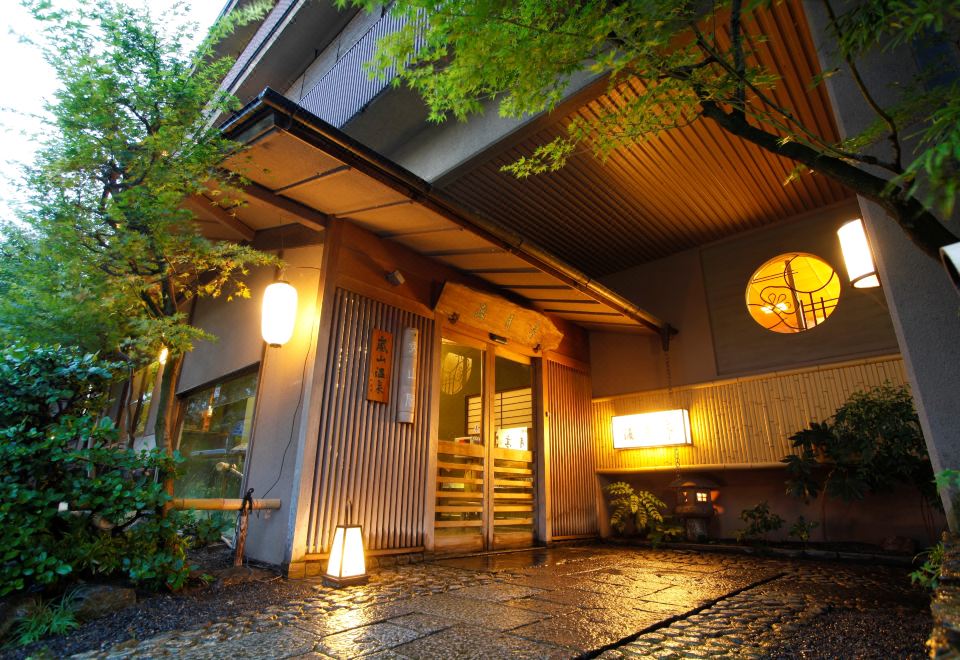 A lantern-lit entrance with wooden doors and surrounding greenery.