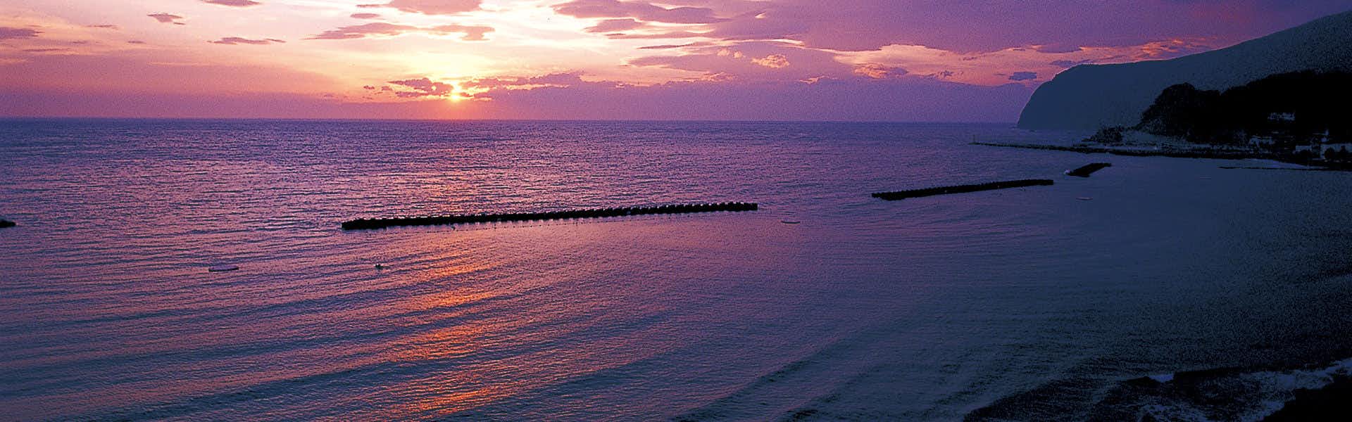 Tatami Inn Yunohama-tei with a sunset panorama across the calm coastal water.