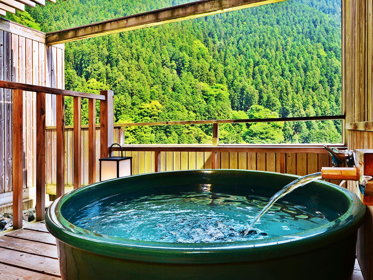Sunriver Oboke with a private round ceramic bath overlooking dense green mountains.