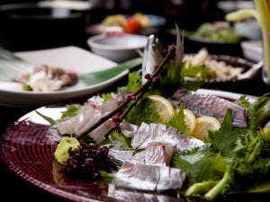 Ryokan Sennari Multiple white and colored plates with prepared food items and green garnish arranged for meal service.
