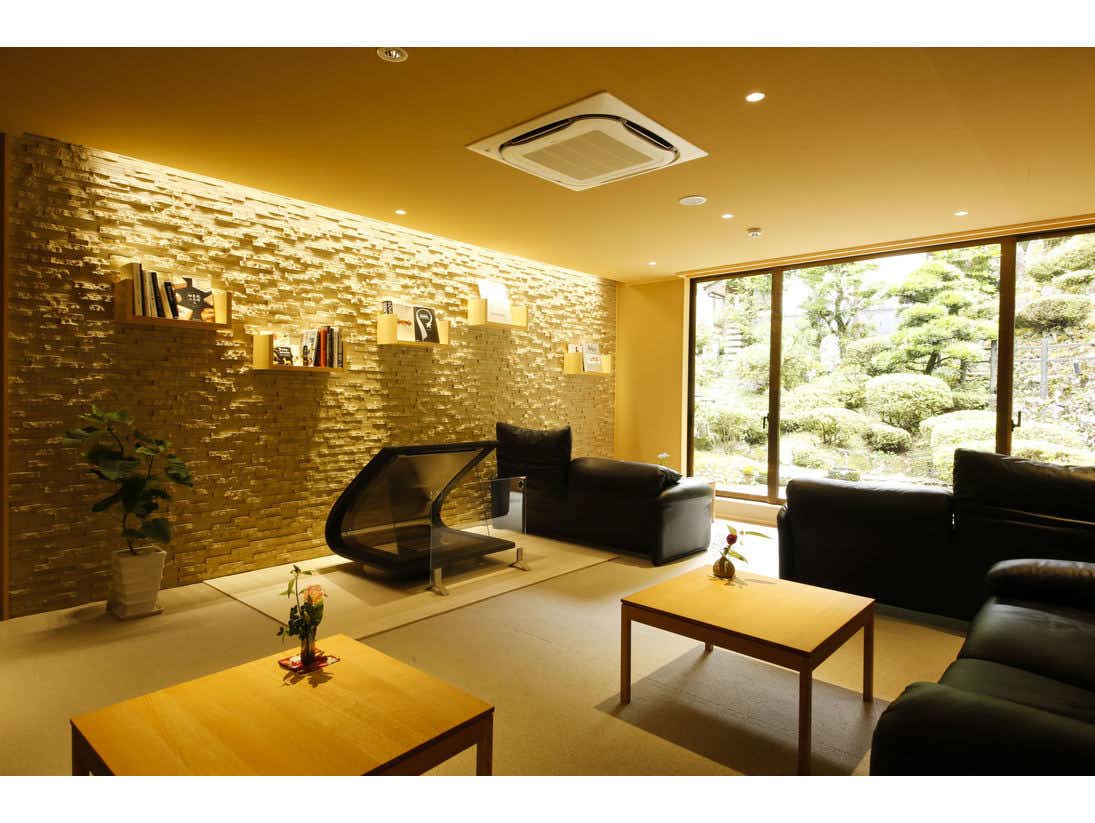 Yuraku Kinosaki Spa & Gardens lobby seating beside a stone feature wall and garden windows.