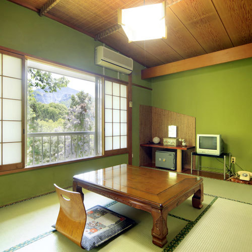A green-walled tatami guest room with a low table and floor chairs.