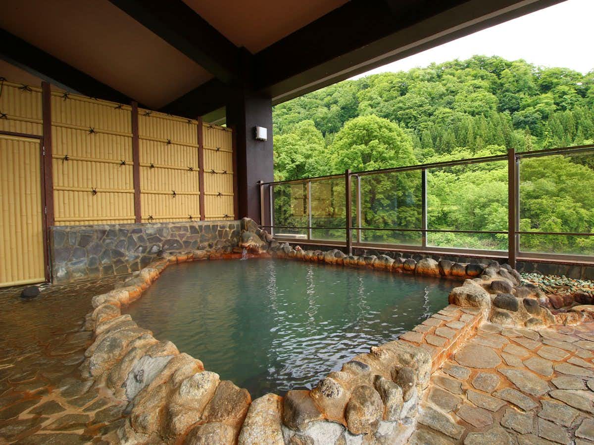 Utto Onsen "Matagi no Yu" with an open-air stone bath overlooking quiet mountain woods.
