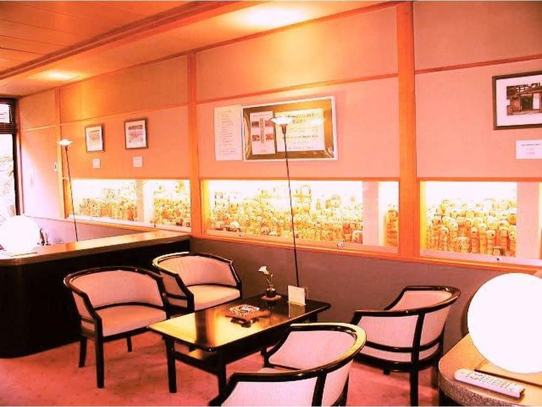 Tokiwokazaderu Yado Wakaba Ryokan with a coral-colored lounge with white armchairs and display shelves.
