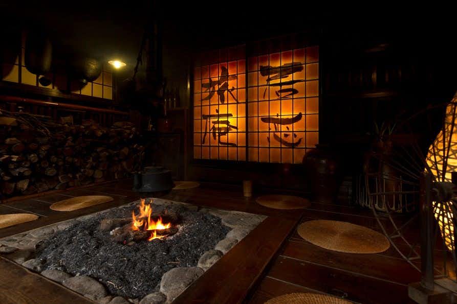 Kurokawa Onsen Ikoi Ryokan with this scene, where an open hearth glows beneath dark beams in a traditional shared room.
