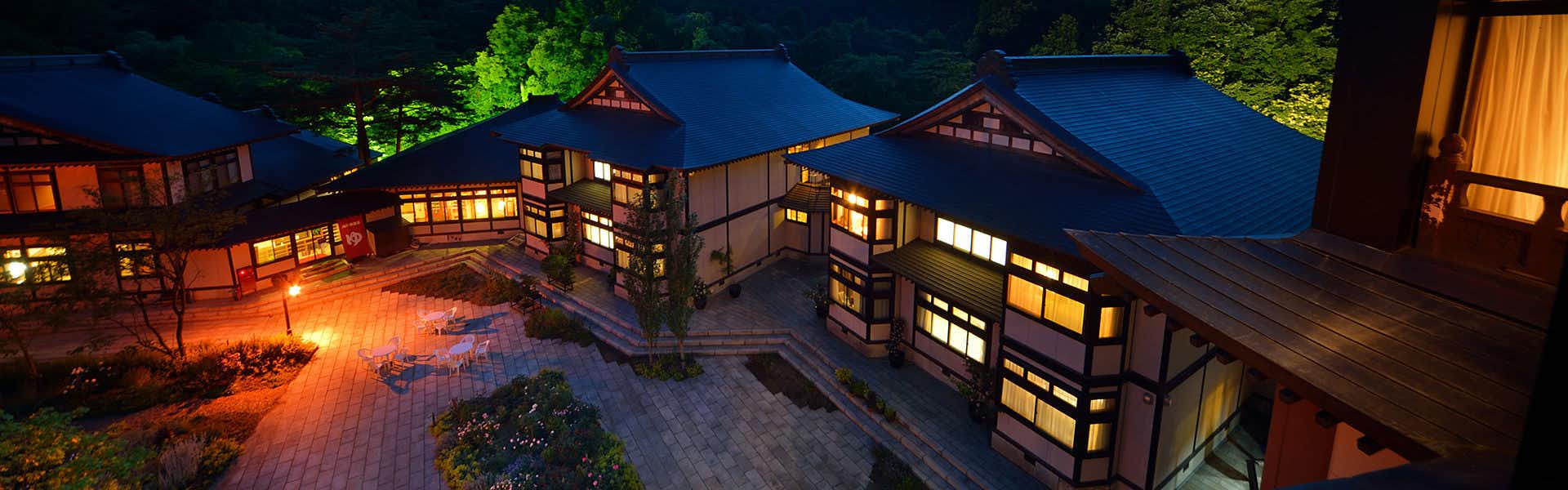 Yukaen, Mountain God Onsen with the illuminated inn complex beneath a deep blue evening sky.