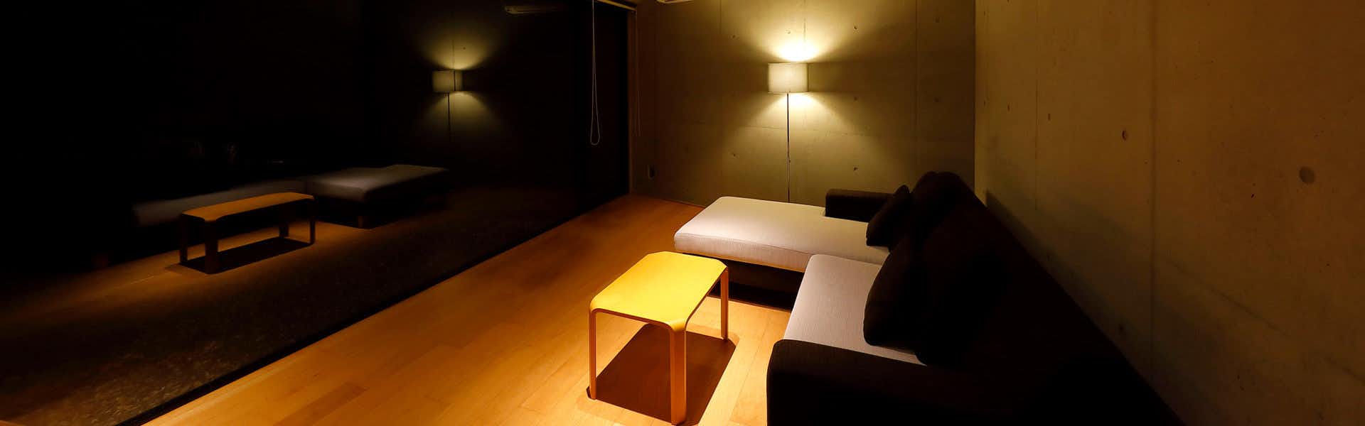 Ryokan Konomama with a modern bedroom with warm bedside lighting and dark walls.