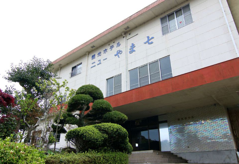 The lodging facade beside clipped trees and shrubs.