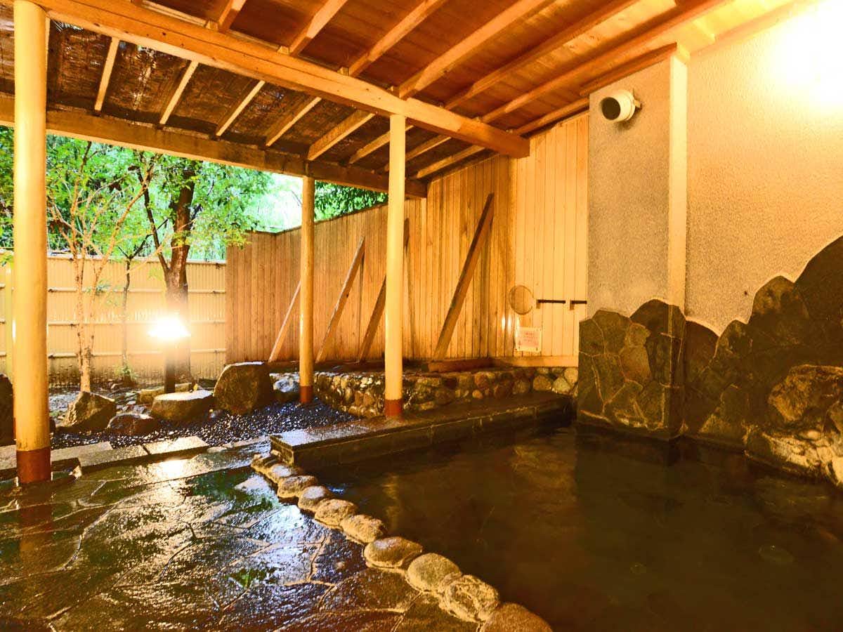 Arima Zuihouen with an open-air rock bath sheltered beneath timber rafters.