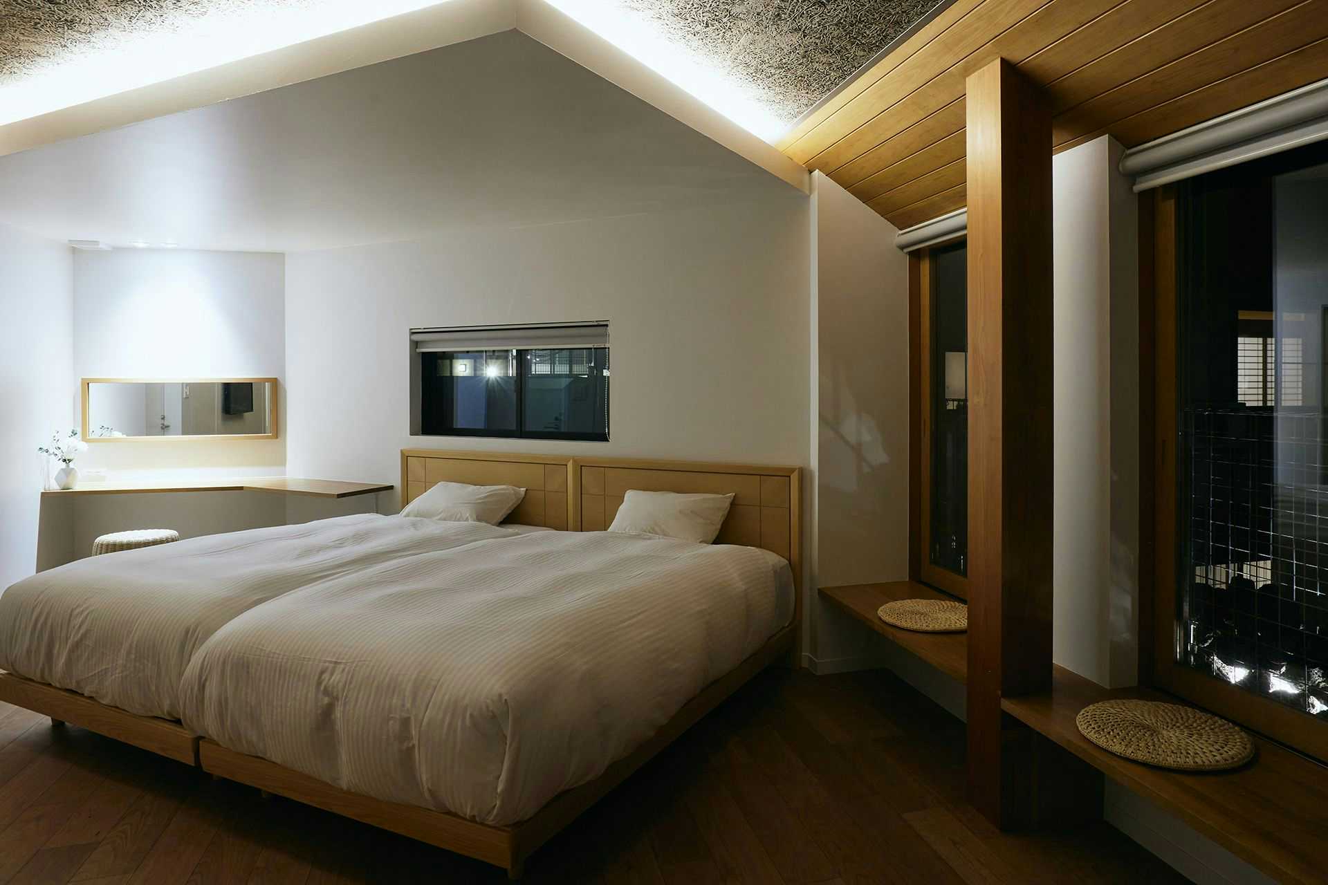 Kinosaki Onsen Tsuchiya Ryokan with a modern twin bedroom beneath an angular timber ceiling.