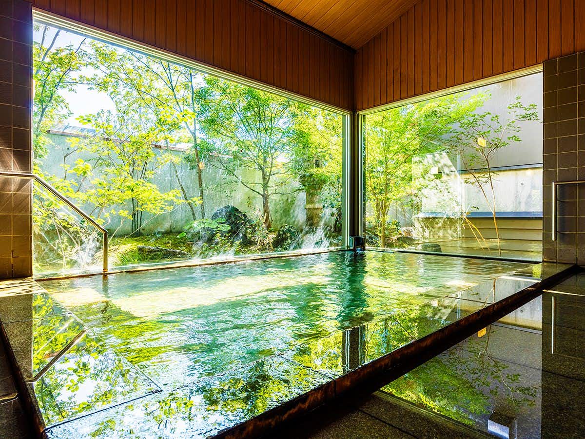 Onsen Ryokan Marumo indoor bath lined by corner windows onto a leafy garden