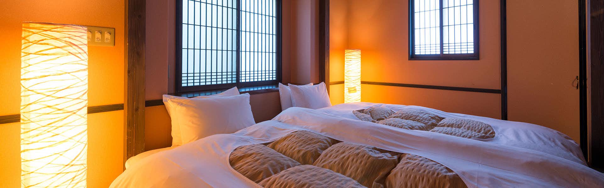 Suisyanoyado syouen with a warmly lit twin bedroom with patterned bedding.
