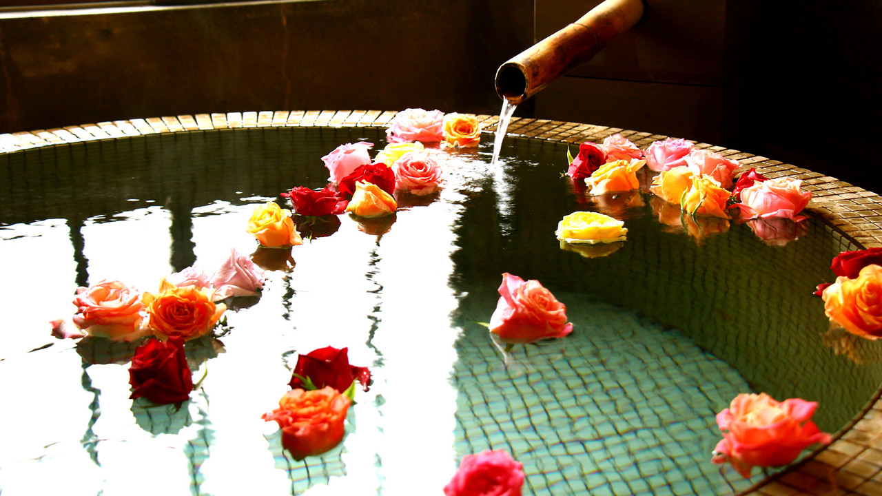 A bath filled with floating flowers.