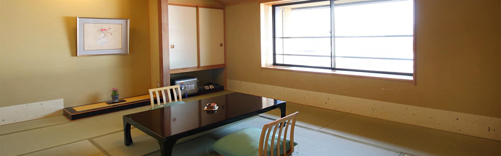 Ryokan Sakaya Dark wood architectural features with black table in foreground and gridded windows with warm interior lighting.