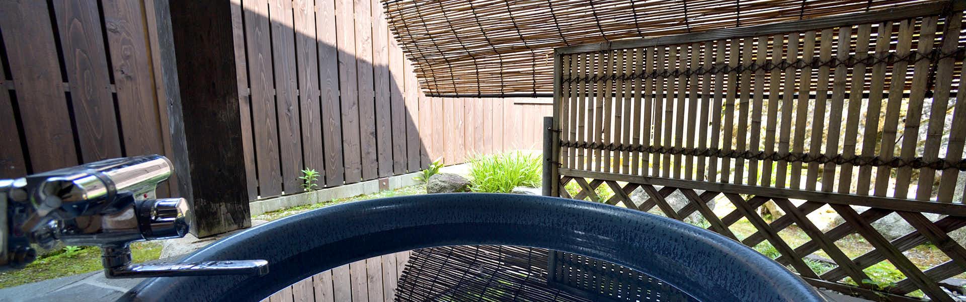 Ryokan Kiyokawa round blue outdoor bathing basin beneath slatted roof with dark wooden walls and latticed gate