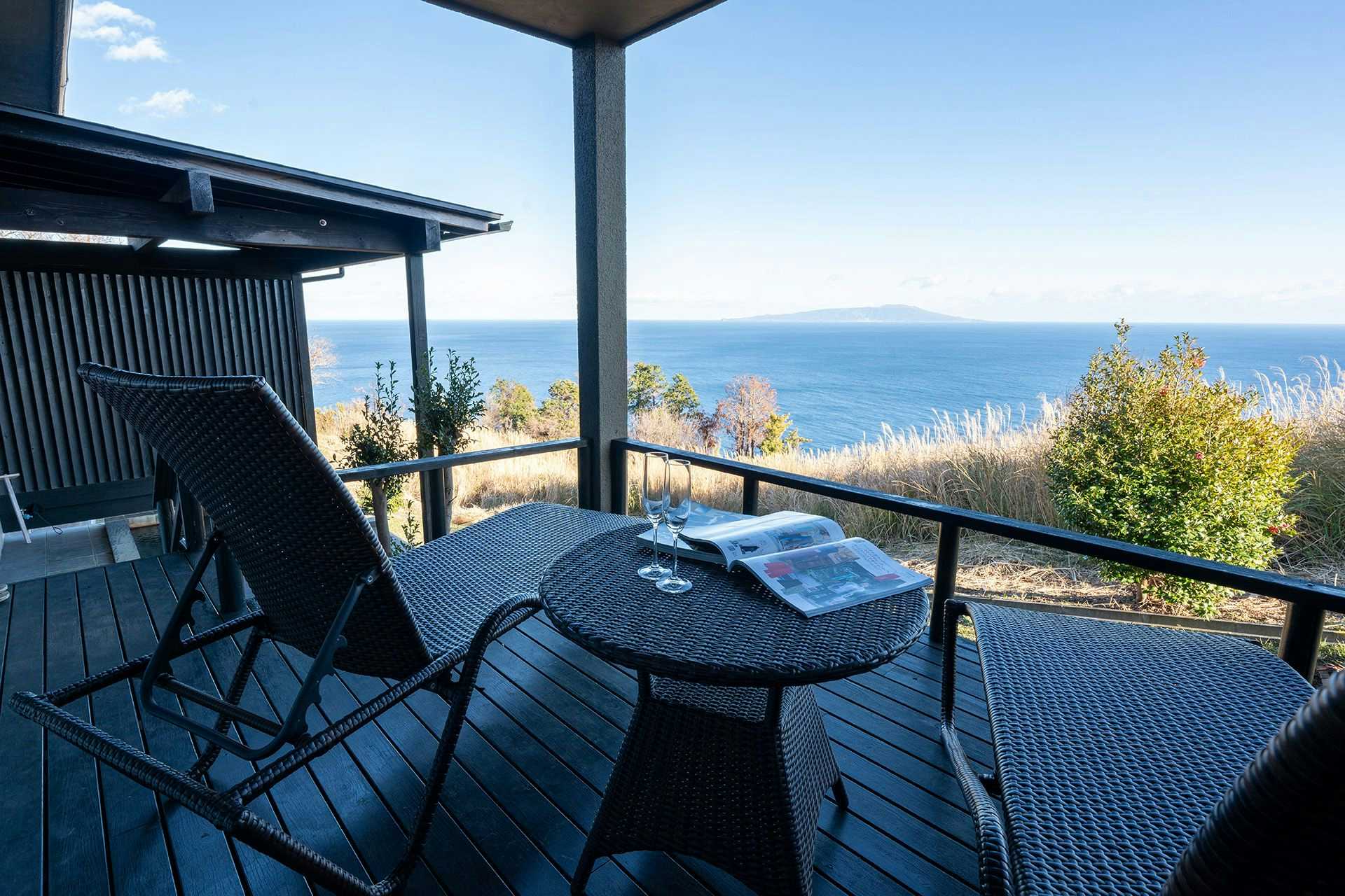 Onyado Fuugetsu Muhen with wicker balcony seating above the deep blue ocean.