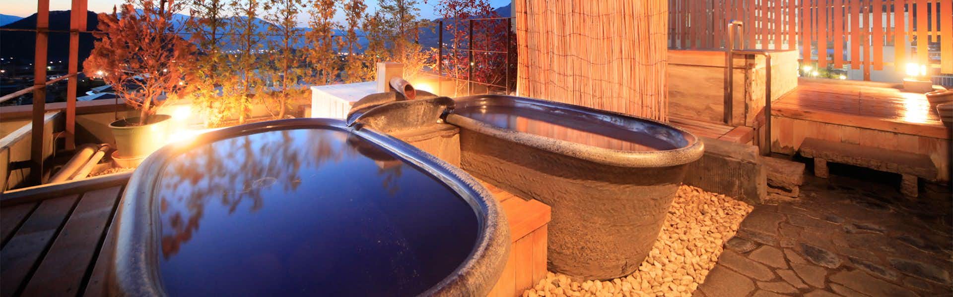Hotel Tsubakino Stone-lined interior basins with windows framing forest scenery.