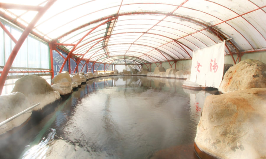 The expansive covered open-air bath surrounded by natural rock.