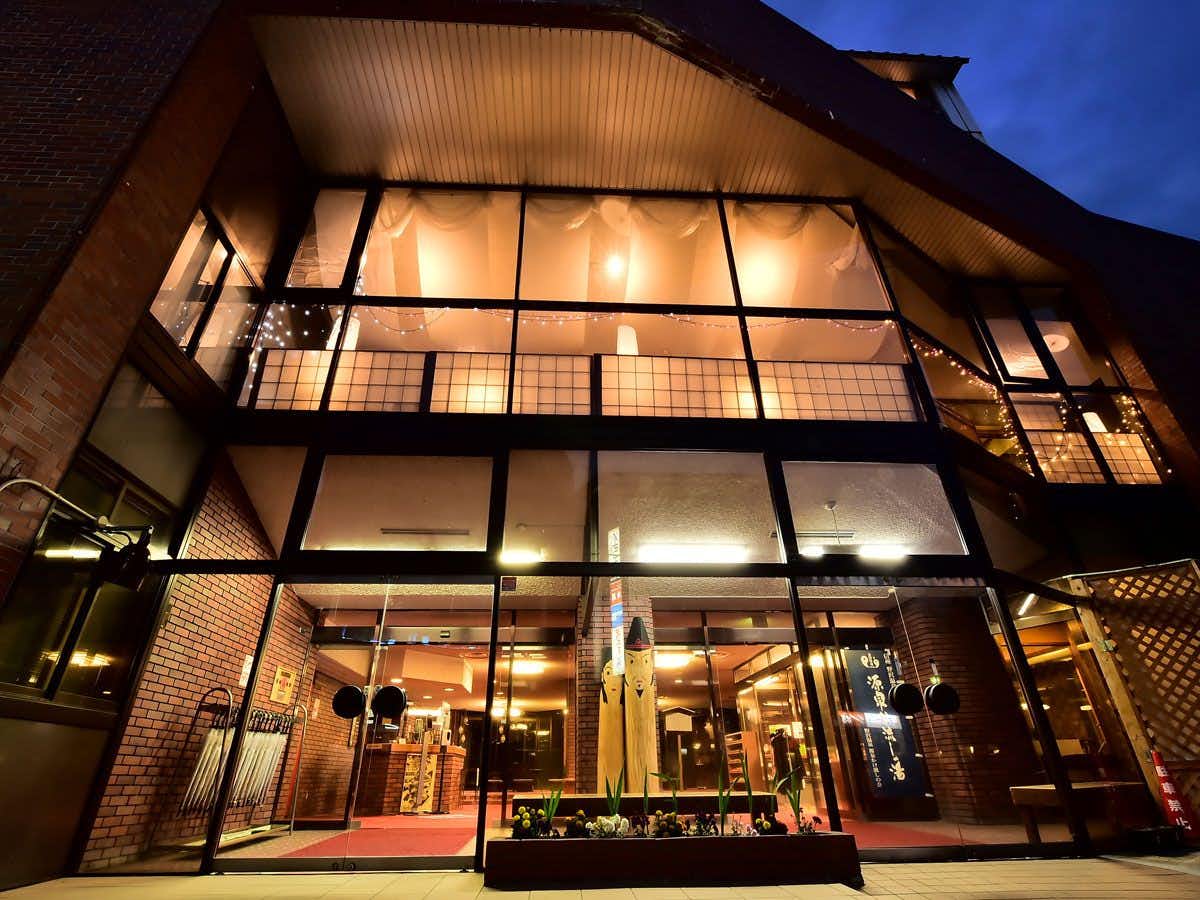 Nozawa Onsen Asahiya Ryokan with the glass-fronted entrance glowing beneath steep timber eaves.
