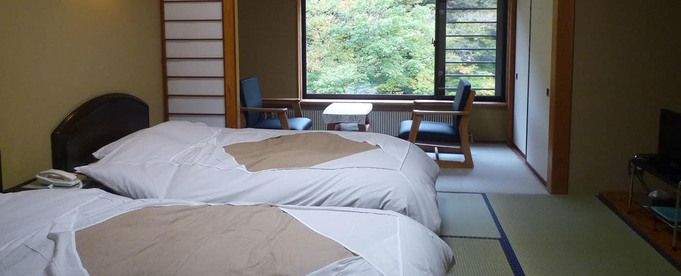 Kawako Onsen Hamaya Ryokan with a twin bedroom with tatami flooring and forest window.