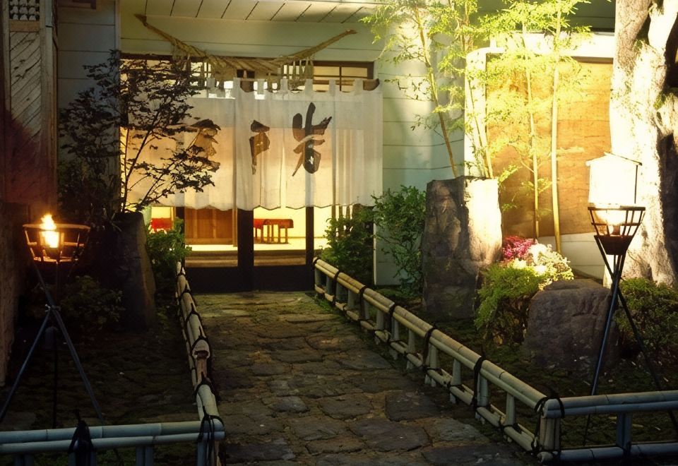 A stone path between small lanterns leads to an illuminated entrance.