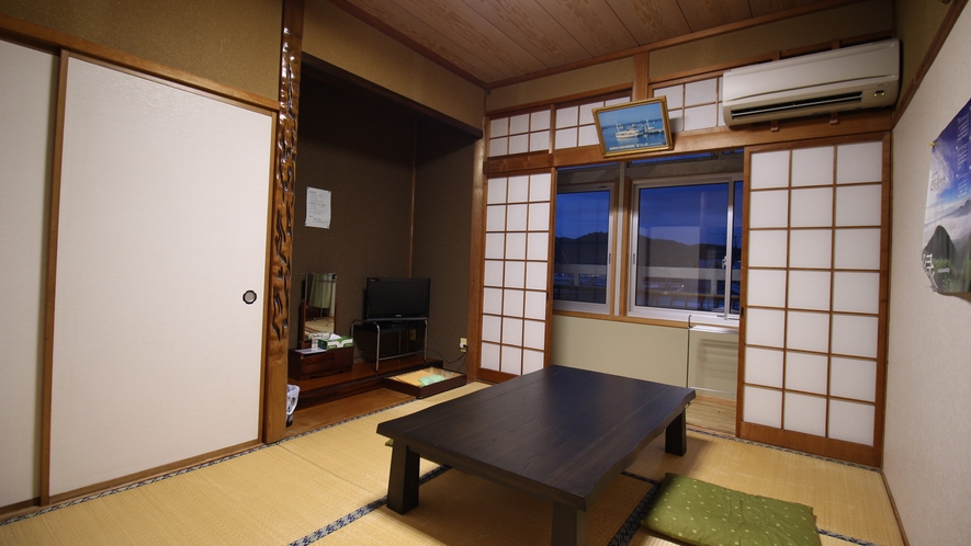 A tatami guest room with a television and low table.