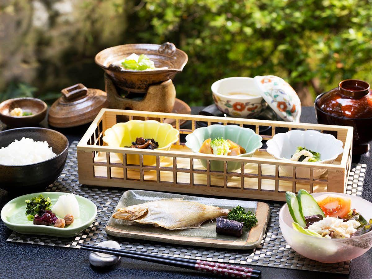 Onsen Ryokan Marumo meal arrangement spread across small plates and bowls beside greenery