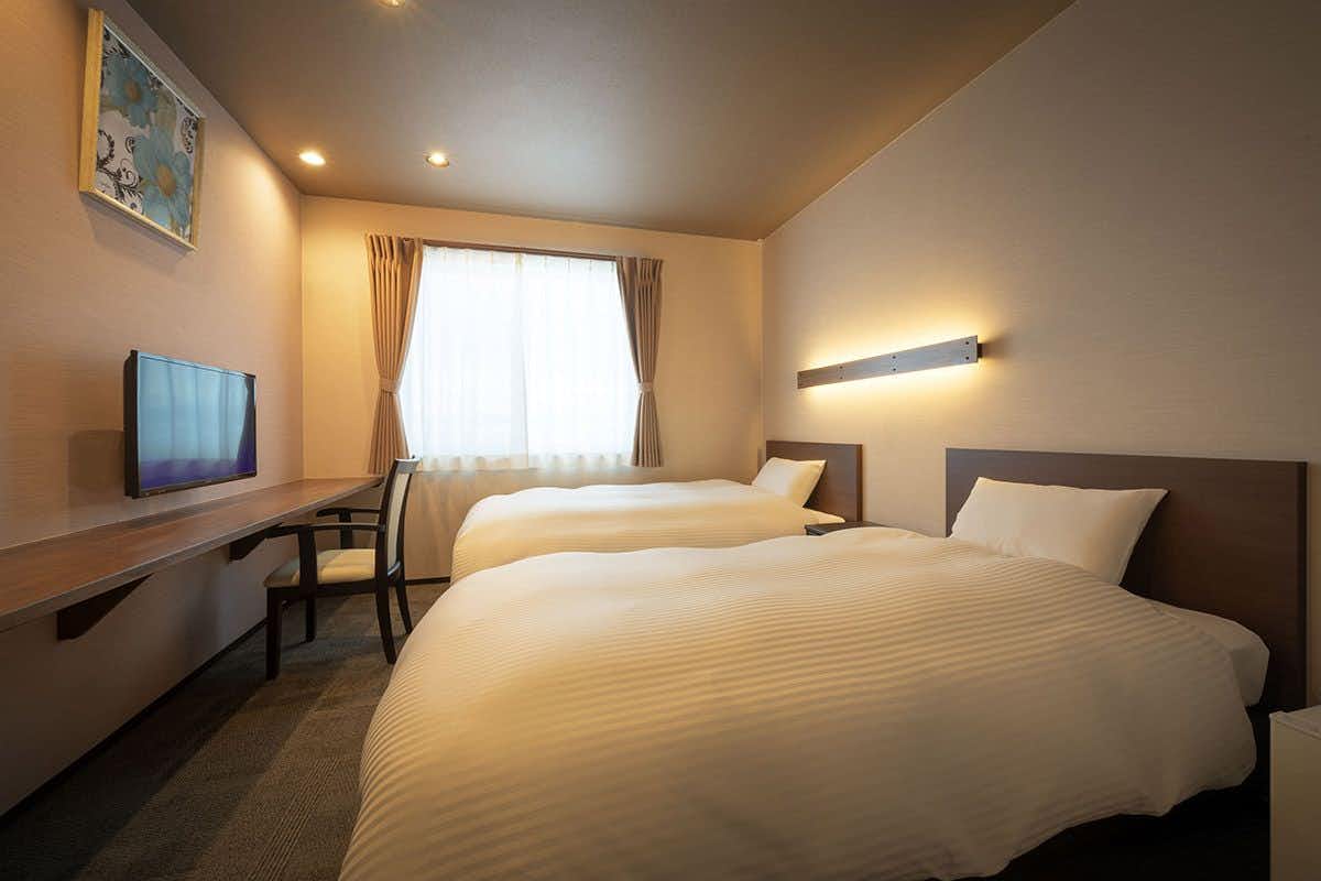 Ryokan Maizuru with a modern bedroom with white bedding and projected landscape view.