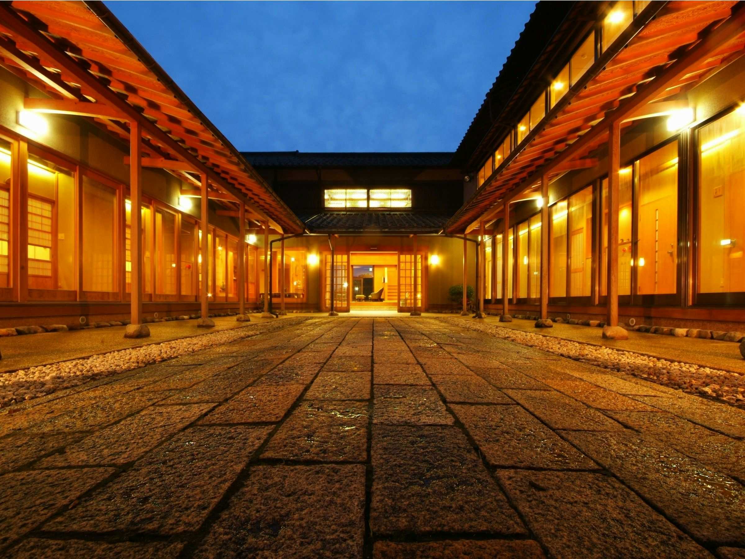 Nishitaniya Kaika with a lantern-lit timber corridor surrounding a gravel courtyard.