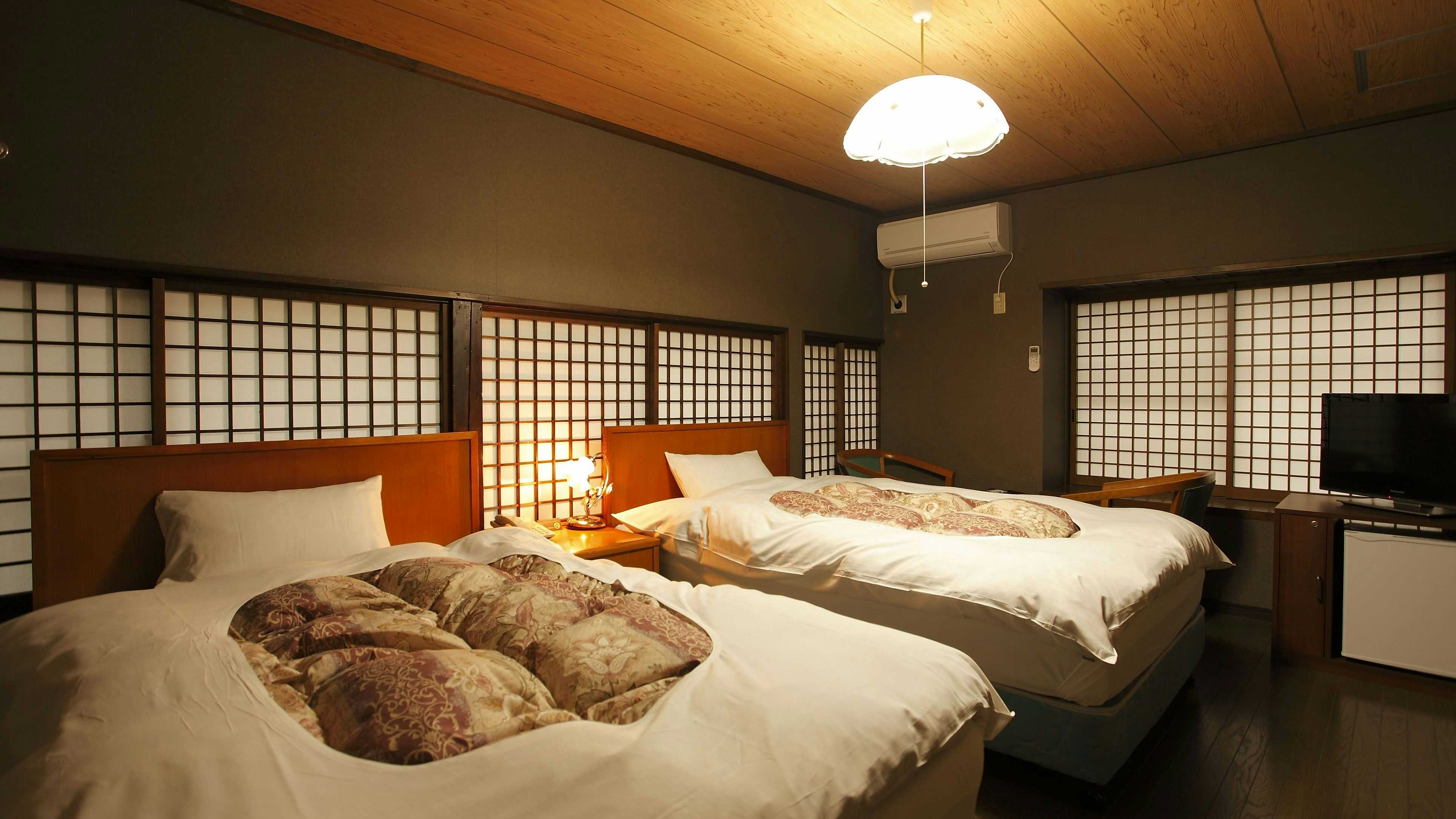 Ryokan Tagoto twin beds in a wood-trimmed room lined with shoji panels