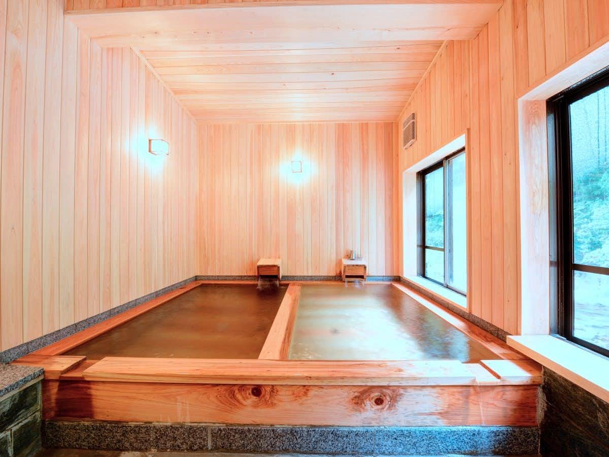 Motoyu Ryokan Daikokuya with a rectangular timber bath beneath pale wooden walls.