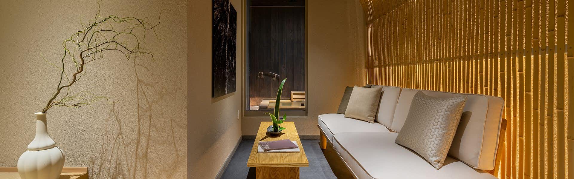 Nazuna Kyoto Tsubaki Street with a compact bedroom with green daybed and warm wooden walls.
