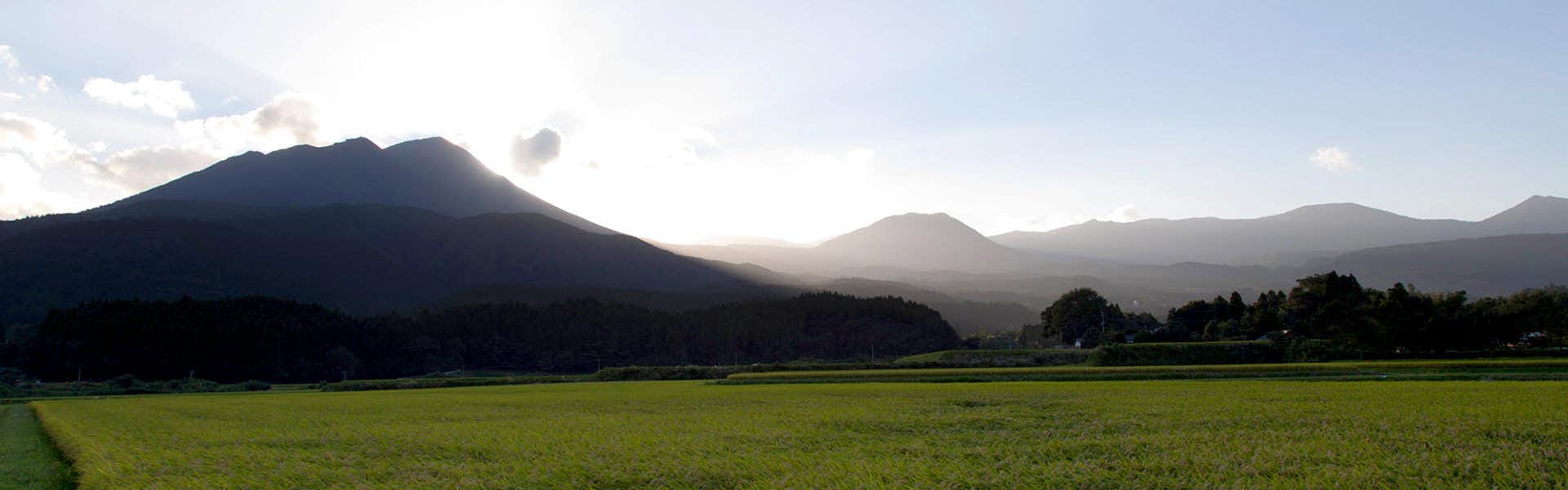 Gokuraku Onsen Takumi no Yado with a wide view across green fields toward layered mountains.