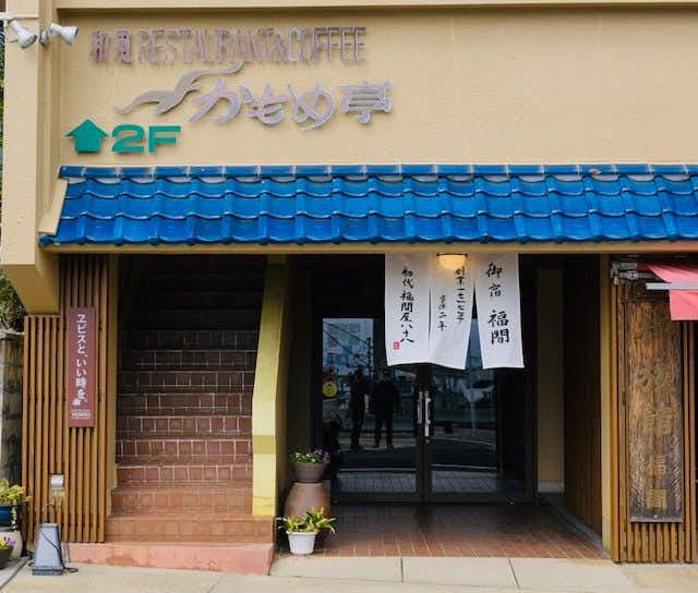 Fukumakan with the entrance beneath a blue awning and property sign.
