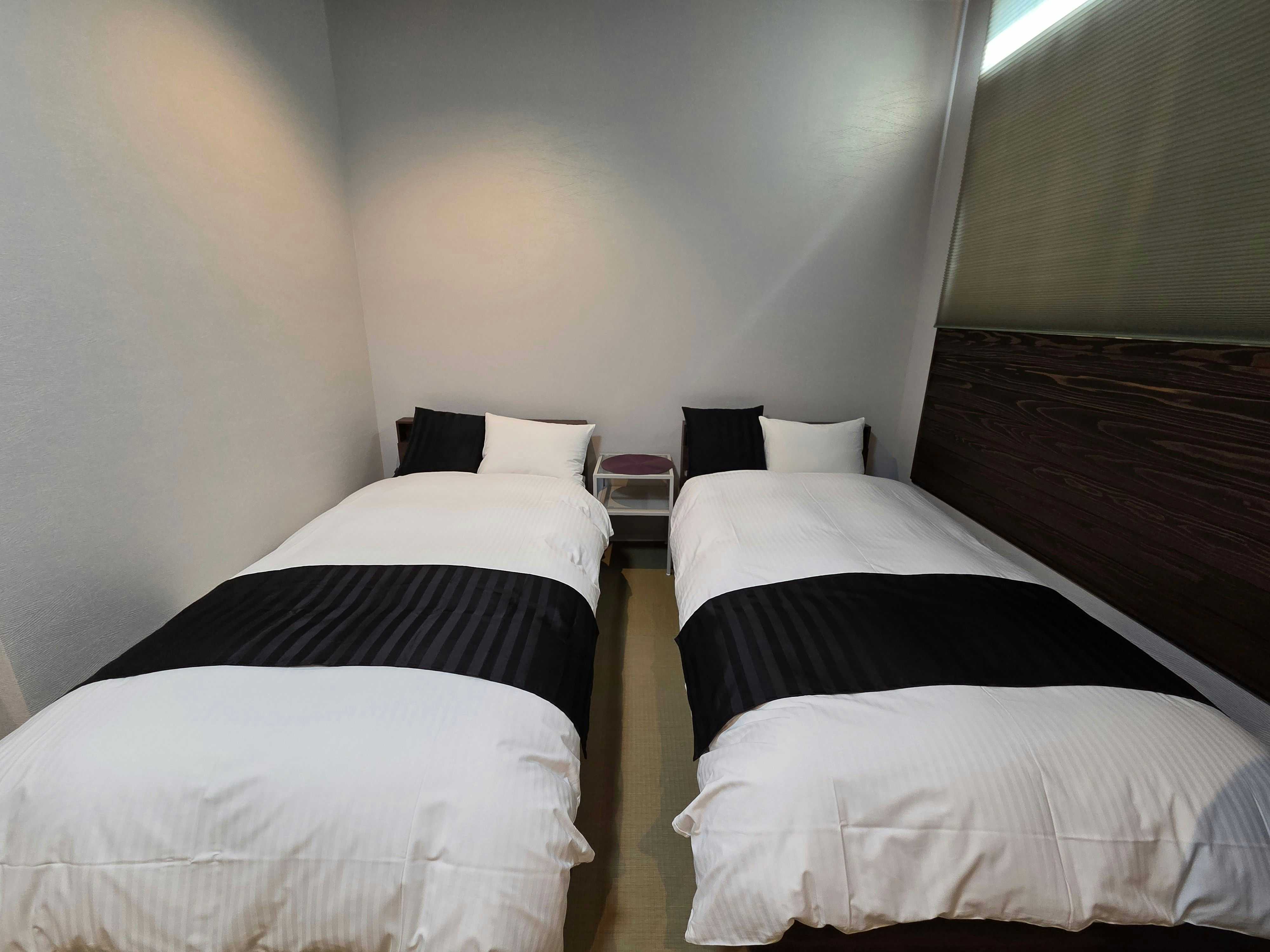 Ryokan Yamato-ya with a modern twin bedroom with black runners and pale walls.
