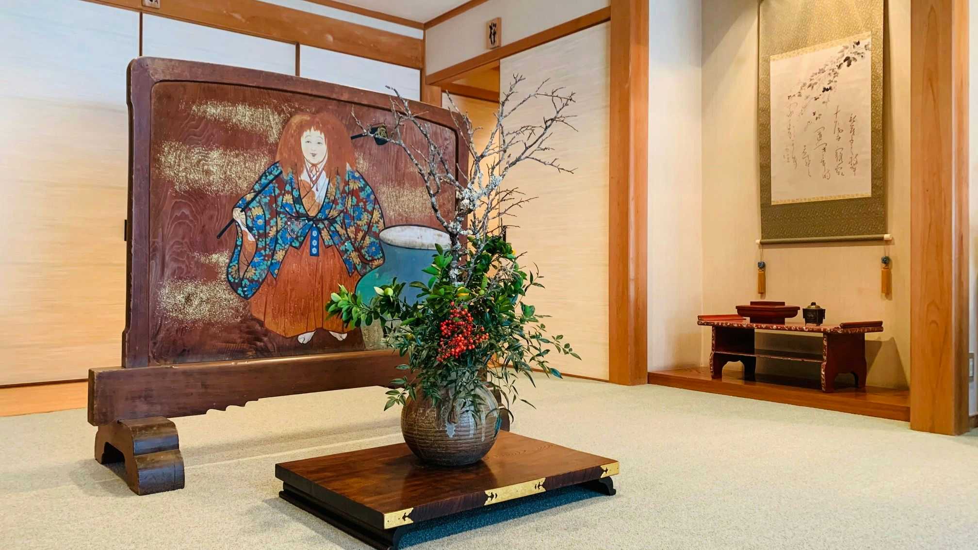 Yoshino-kan: An Accommodation Where You Can Stay "Your Way," Even Alone with a flower arrangement beneath carved traditional artwork.